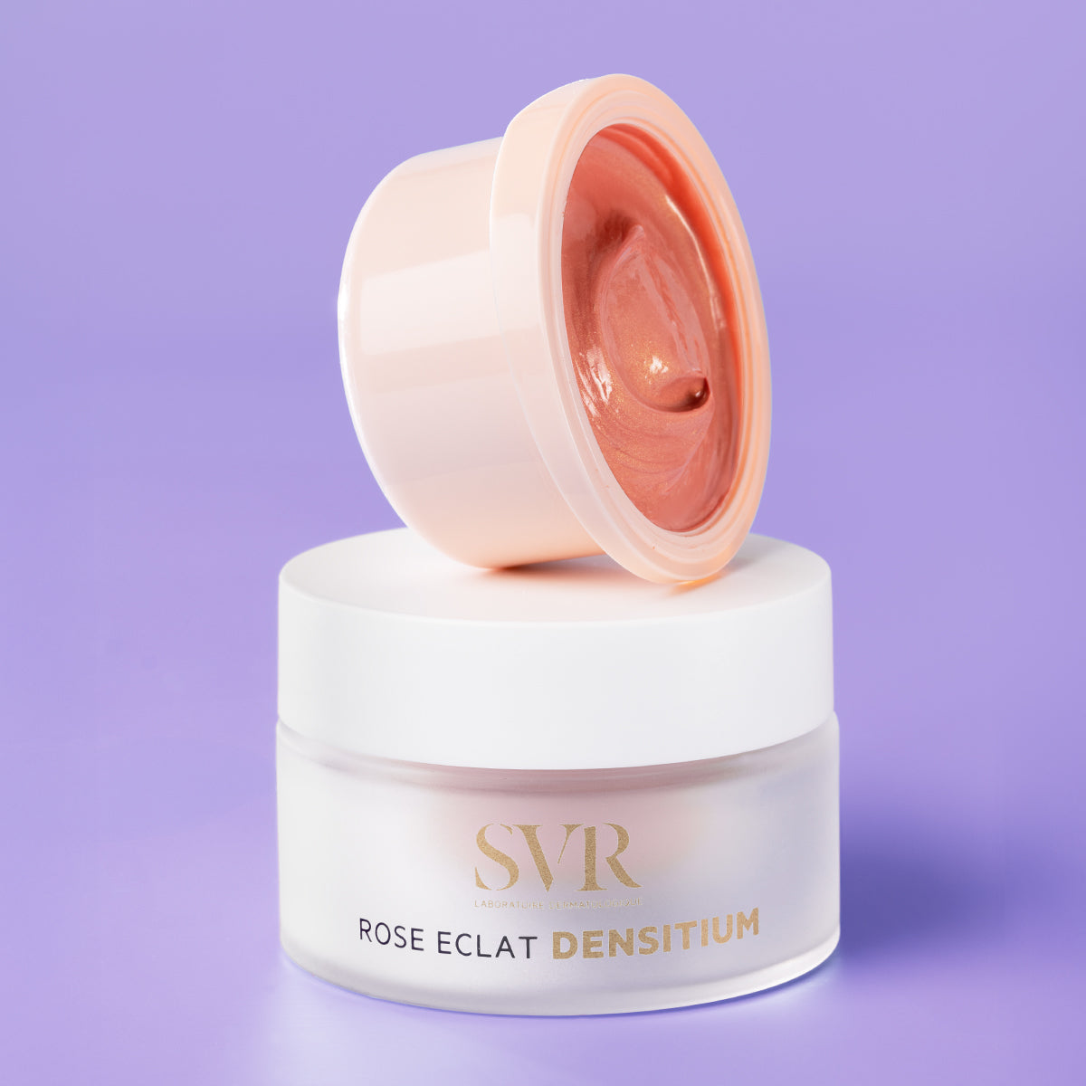 SVR Densitium Rose Éclat refill pod resting on a frosted glass jar against a purple background.