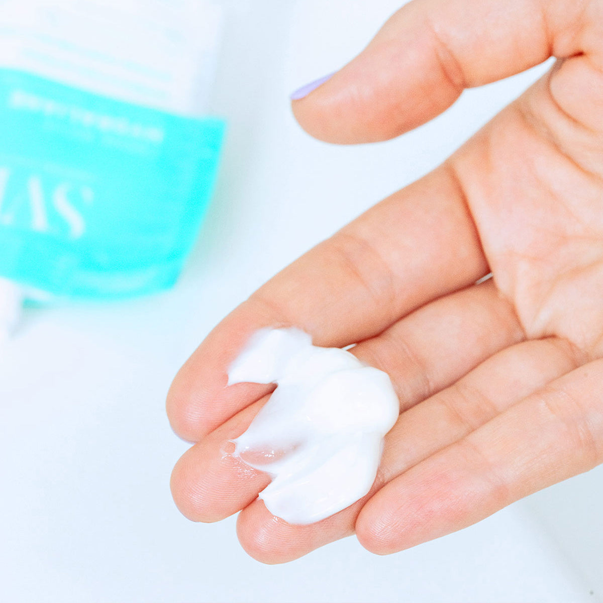 Texture riche et onctueuse de la crème hydratante Hydraliane déposée dans la paume d'une main, avec son emballage éco-conçu.