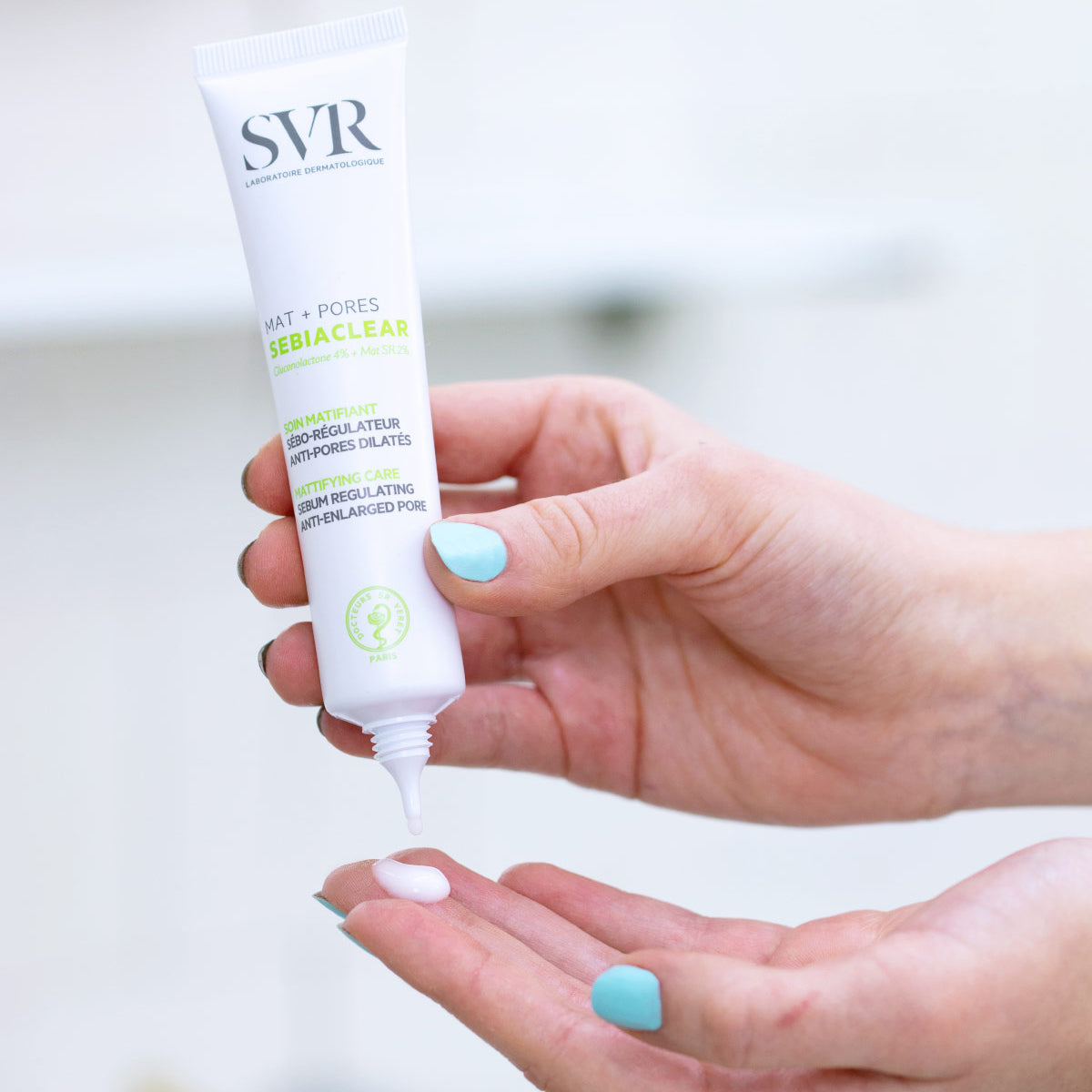 Tube blanc de soin matifiant SVR Sebiaclear Mat+Pores pressé dans la main, délivrant une texture fluide sur la paume.