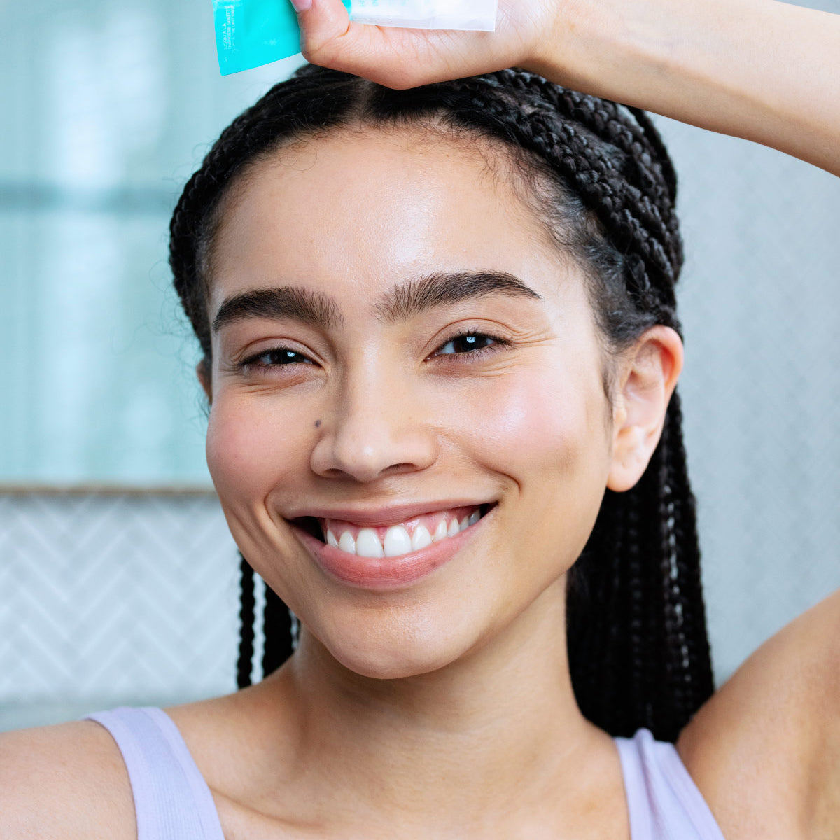 Femme souriante tenant un tube bleu éco-conçu de crème hydratante Hydraliane Riche pour peaux sèches.