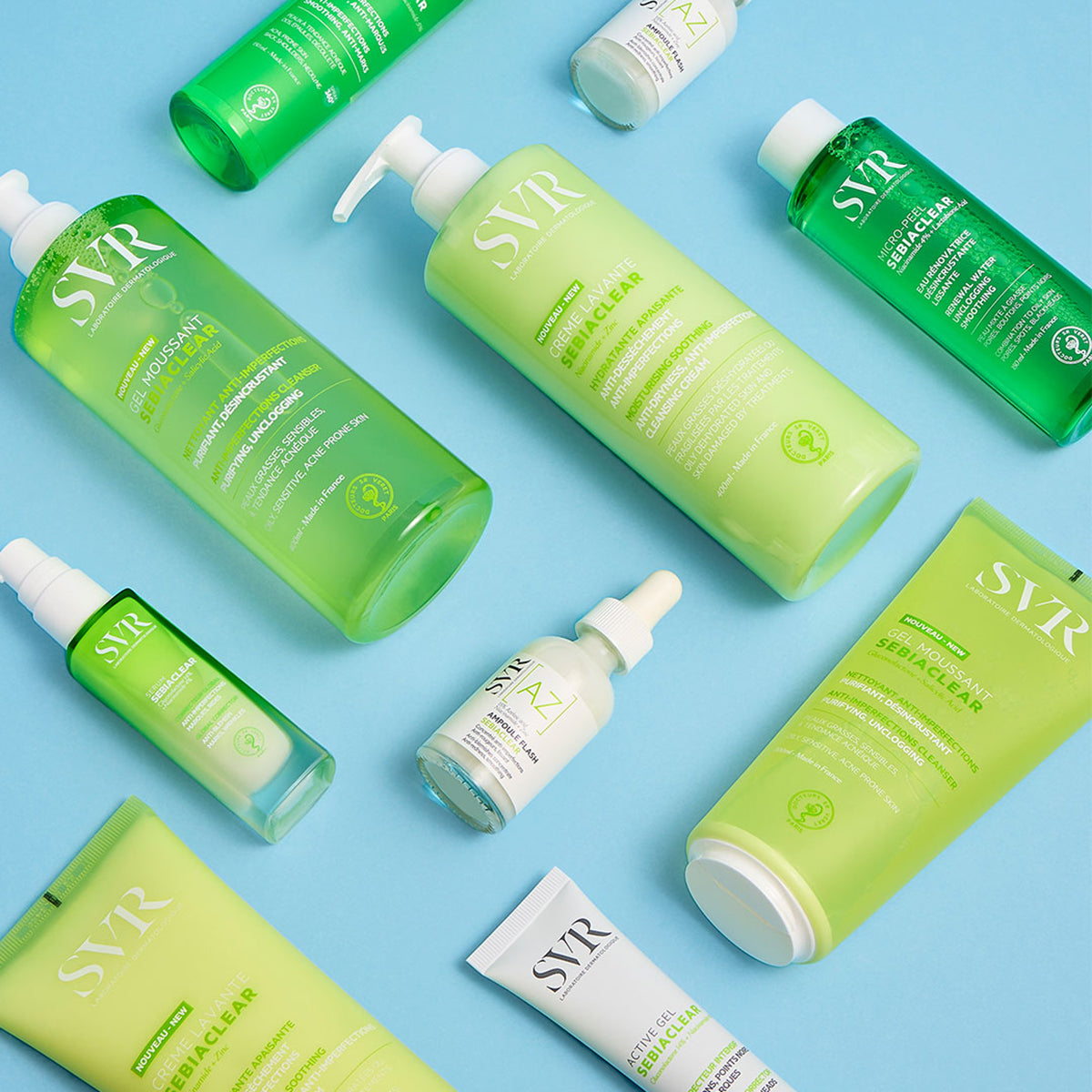 Gamme de soins SVR Sebiaclear : flacons et tubes verts et blancs sur fond bleu clair pour peaux mixtes à grasses.