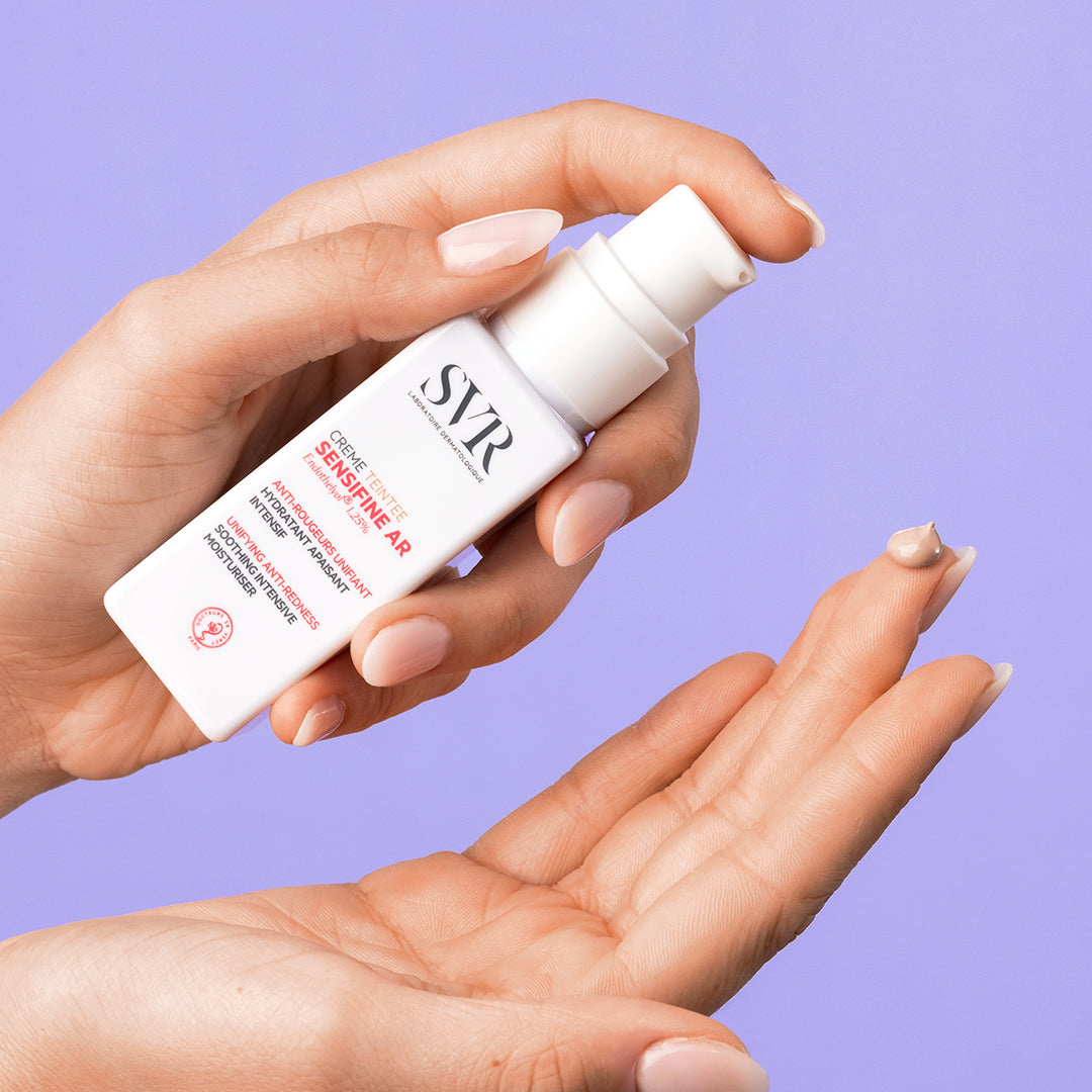 Flacon pompe blanc SVR Sensifine AR Crème Teintée avec une noisette de crème beige sur le bout du doigt.