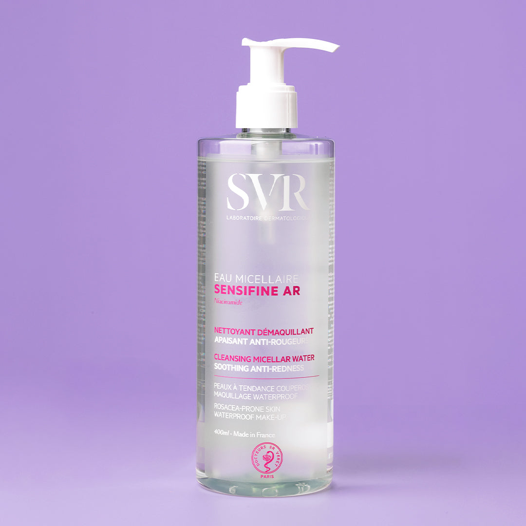 Flacon pompe transparent de 400ml SVR Sensifine AR Eau Micellaire anti-rougeurs sur fond violet.