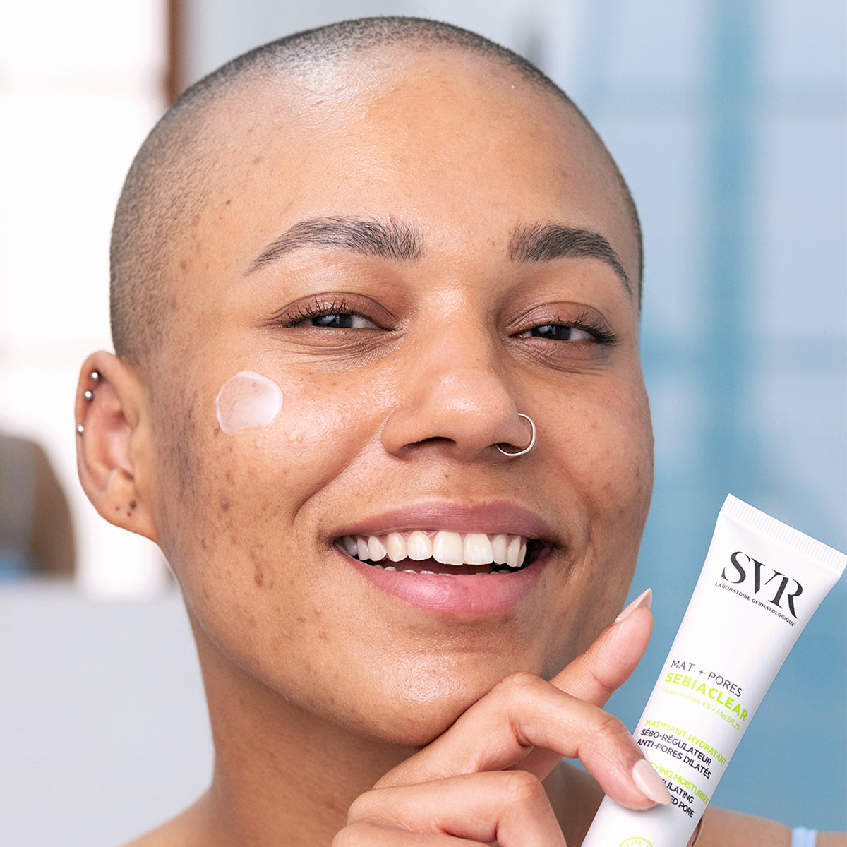 Femme souriante appliquant la crème matifiante SVR Sebiaclear Mat+Pores sur son visage pour réduire les pores et le sébum.