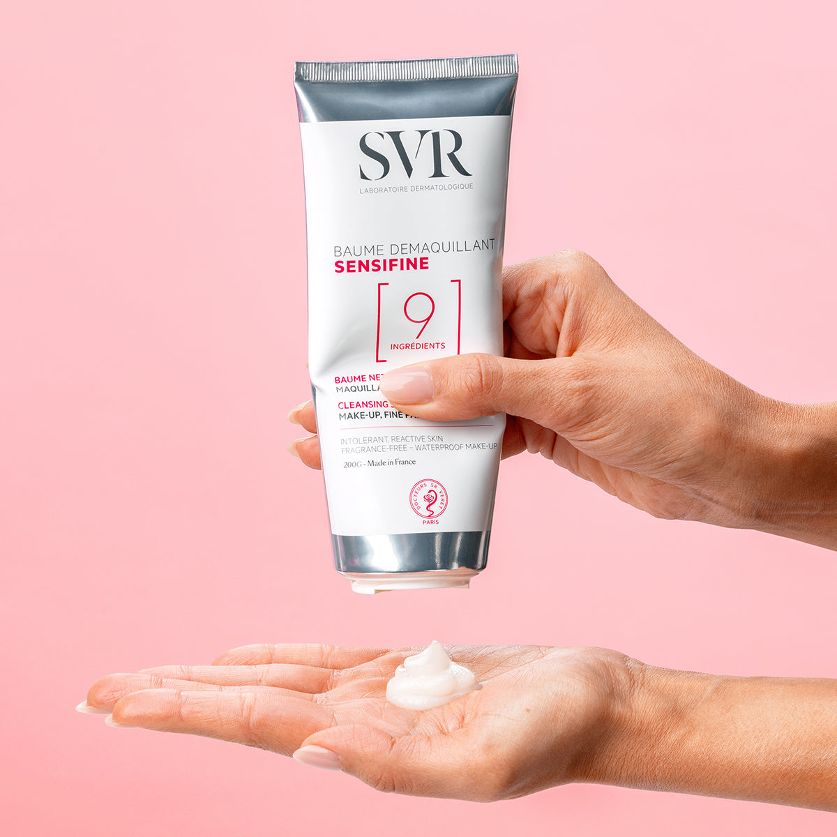Tube de baume démaquillant SVR Sensifine 200g pressé au-dessus d'une main avec une noisette de texture crémeuse blanche.