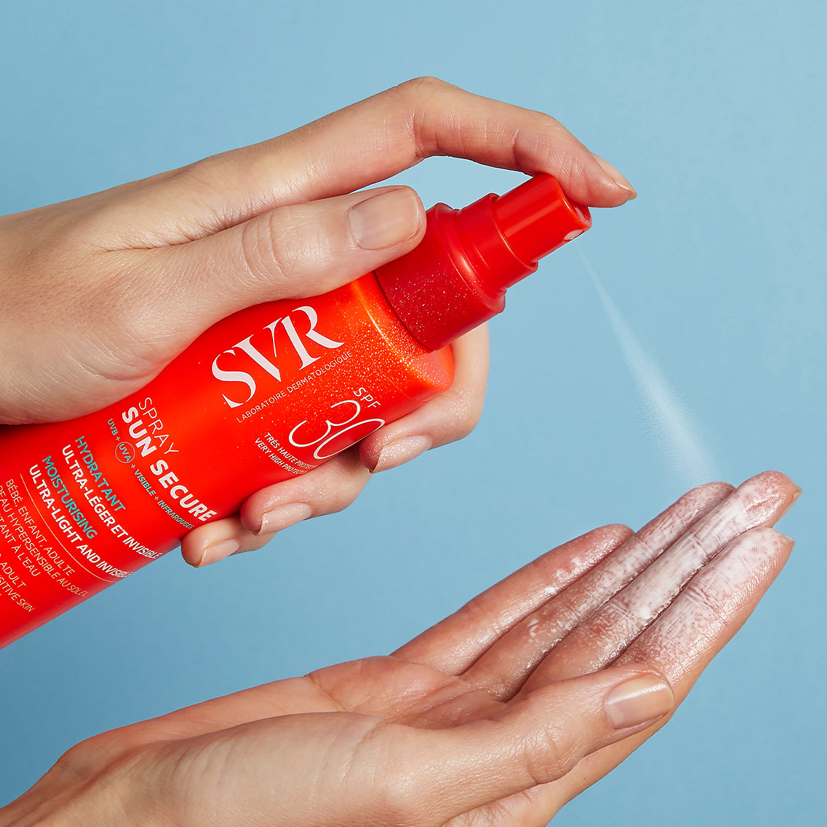 Main tenant un flacon spray SVR SUN SECURE SPF30 orange vif vaporisant une fine brume hydratante sur la paume de la main.