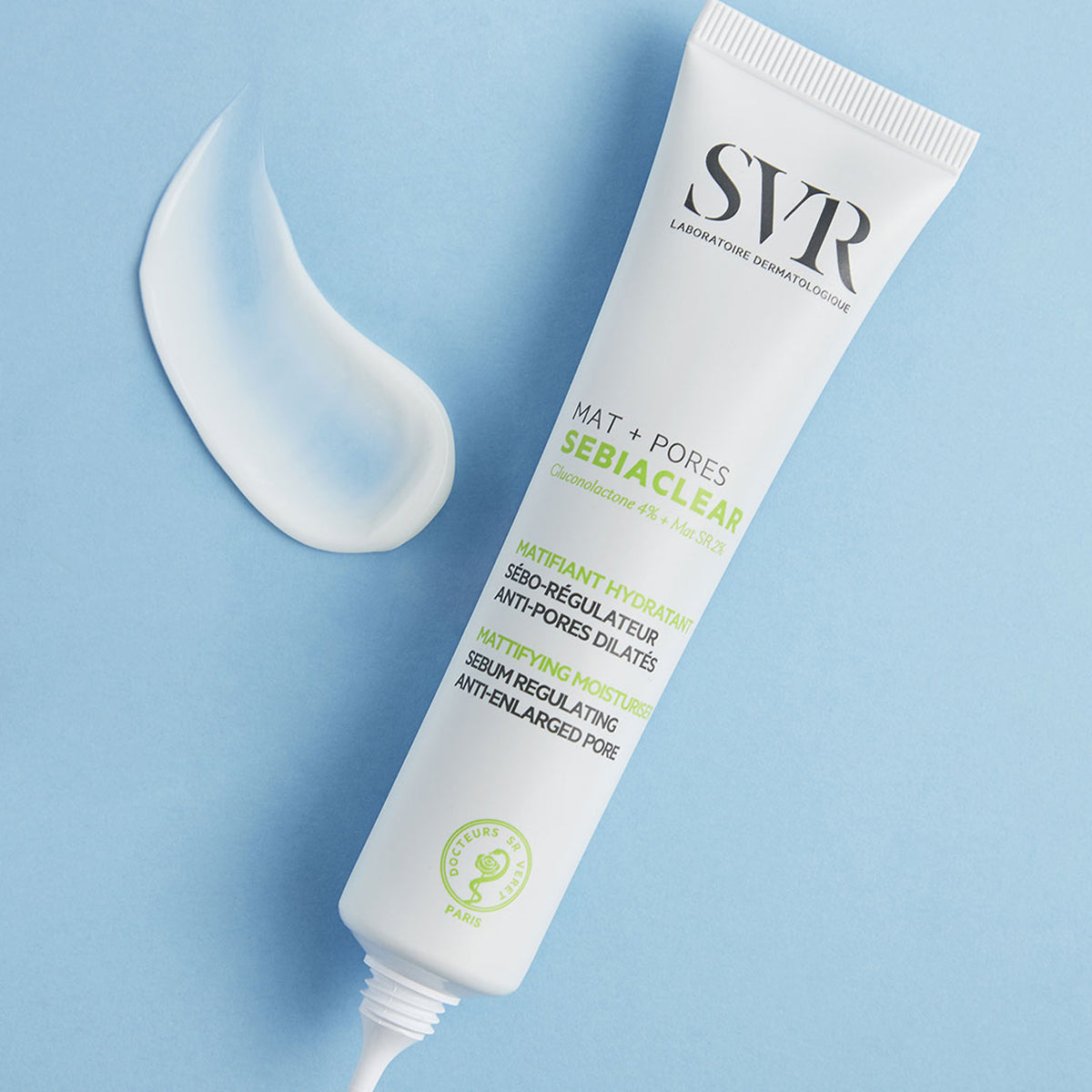 Tube blanc de soin SVR Sebiaclear Mat+Pores avec une noisette de crème fluide sur fond bleu clair.