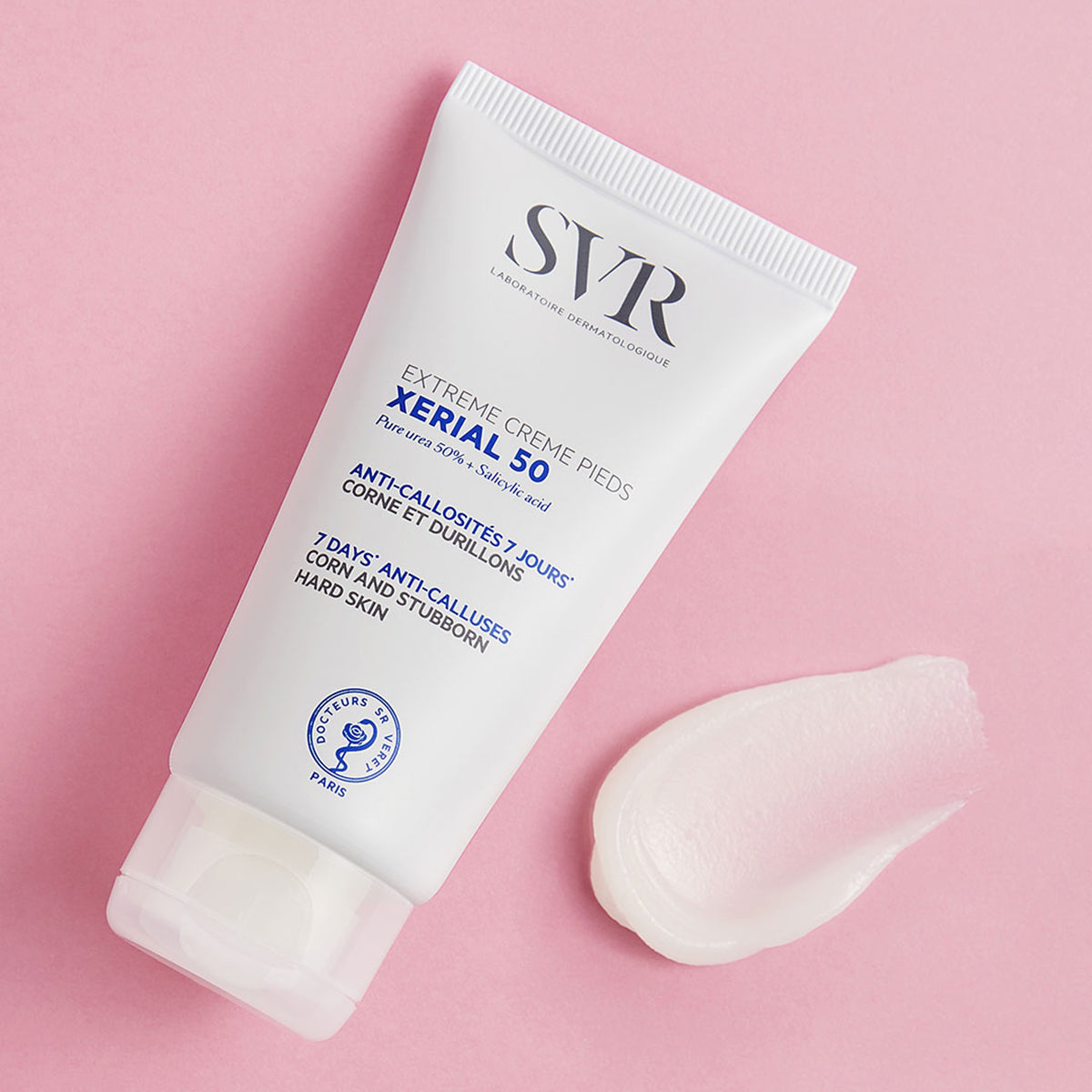 Tube de crème SVR XERIAL 50 pour pieds avec une noisette de texture blanche onctueuse sur fond rose pastel.