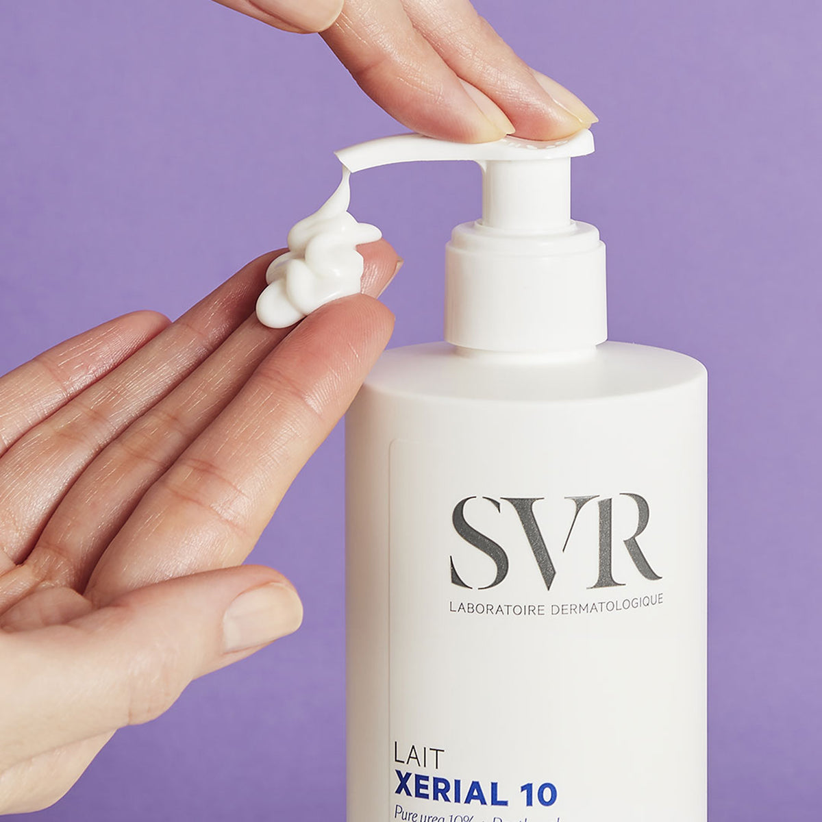Flacon blanc SVR XERIAL 10 Lait avec pompe, texture crème onctueuse déposée sur une main, fond violet.