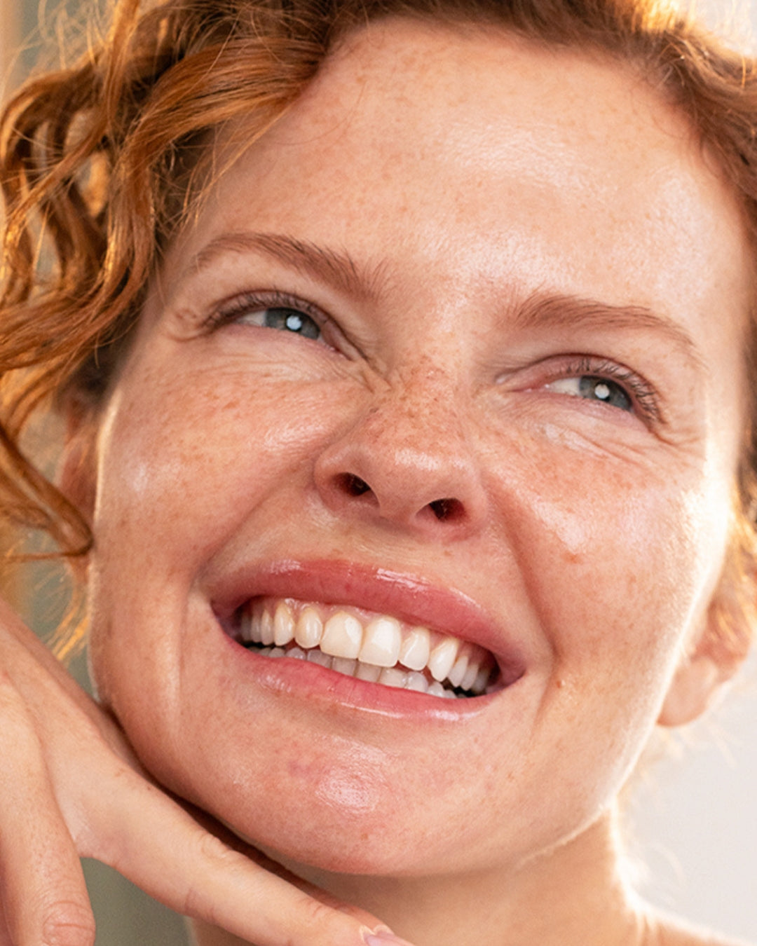Close-up of a smiling woman with red hair and freckles, showcasing radiant, healthy skin for DENSITIUM Bi-Sérum.