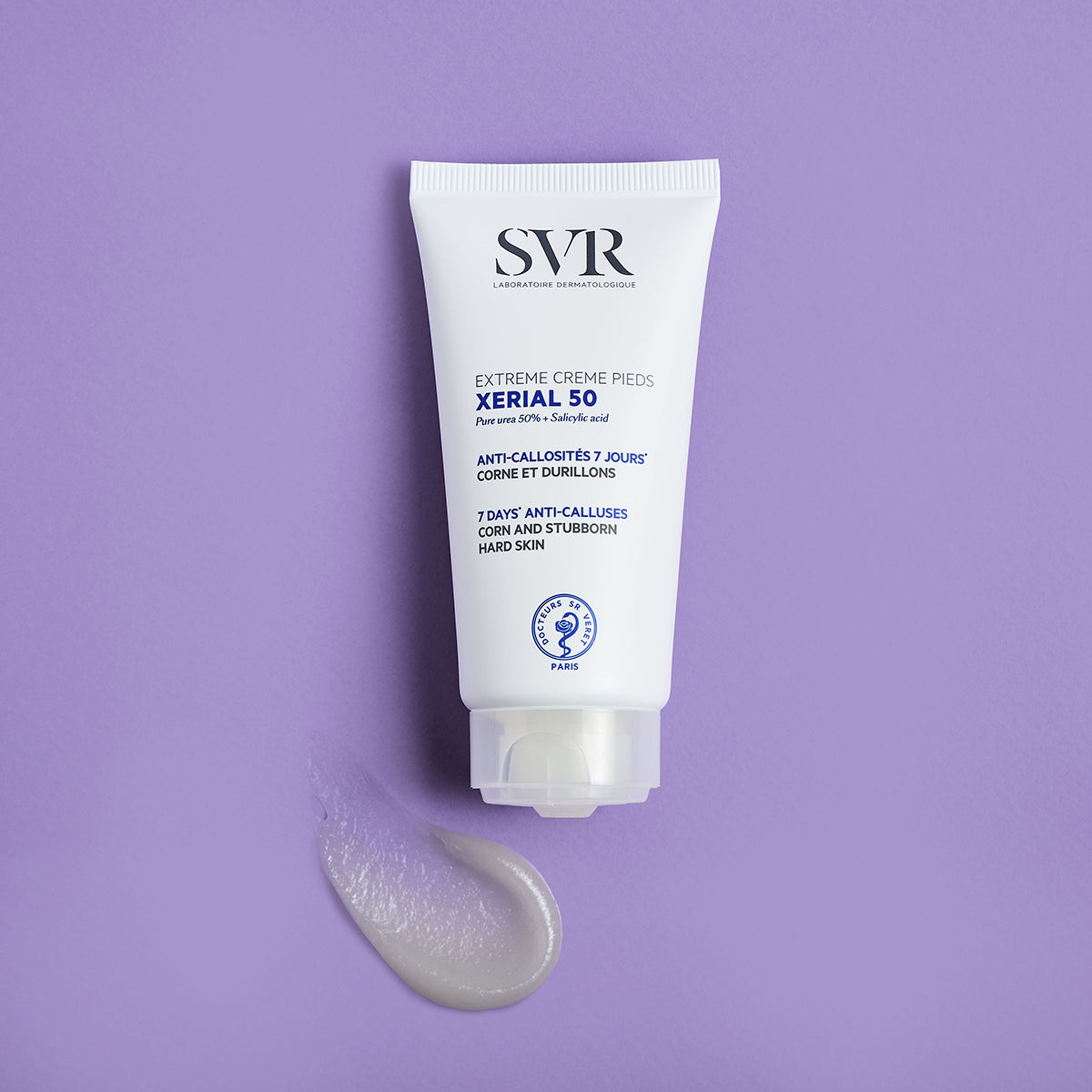 Tube blanc de crème SVR Xerial 50 contre les callosités avec une noisette de produit sur fond violet.
