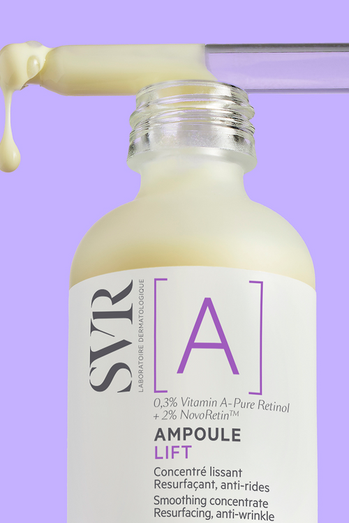 SVR [A] Ampoule Lift serum in a glass bottle with a dropper dispensing creamy yellow retinol formula against a purple background.