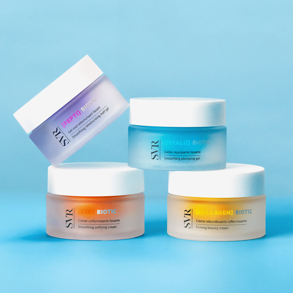 Four SVR Biotic skincare jars in frosted glass with white lids, arranged on a light blue background.