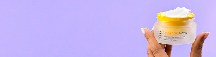 Hand holding a jar of SVR Collagen Biotic firming bouncy cream against a solid light purple background.