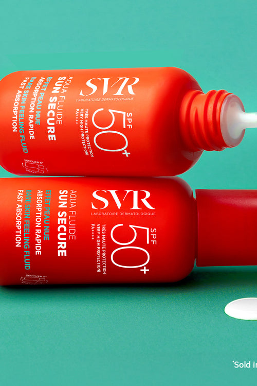 Two orange SVR SUN SECURE Aqua Fluide SPF50+ bottles on a teal background with a drop of white sunscreen fluid.