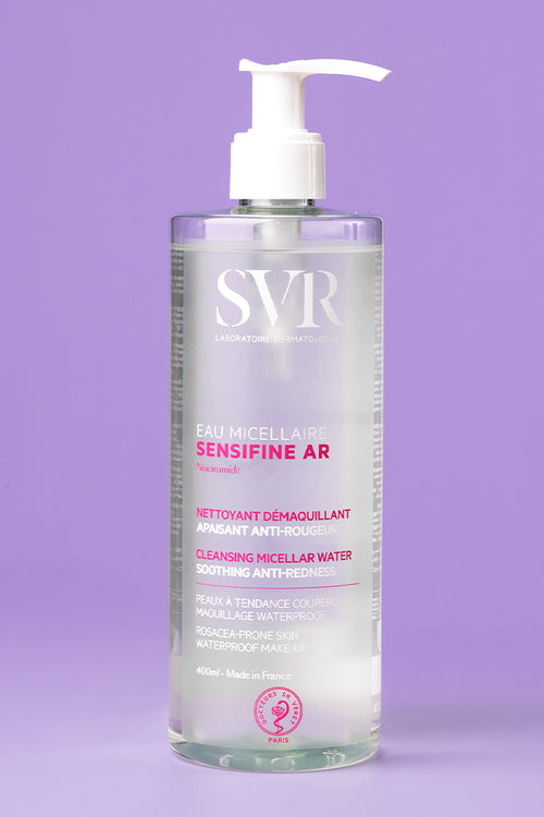 Flacon pompe transparent de 400ml SVR Sensifine AR Eau Micellaire anti-rougeurs sur fond violet.