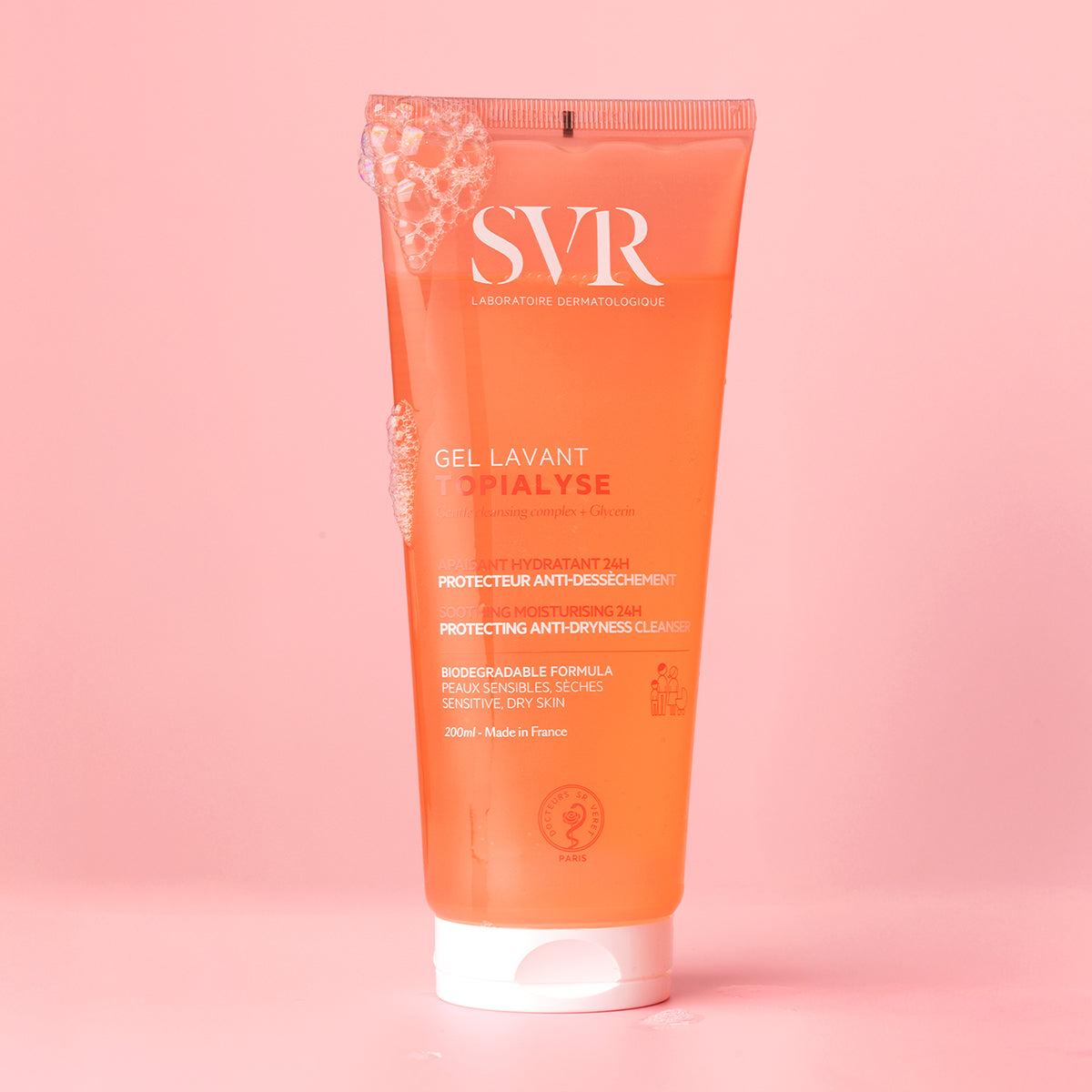 SVR TOPIALYSE Gel Lavant 200ml tube in translucent orange with white text and soap bubbles on a soft pink background.