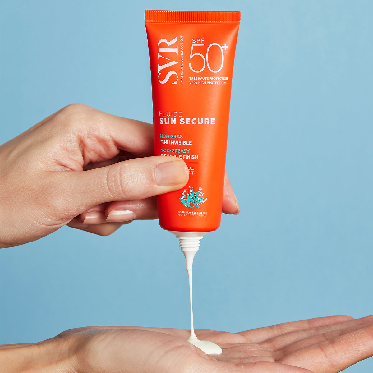 Tube orange de crème solaire SVR Sun Secure SPF50+ pressé pour appliquer une texture fluide sur une main.